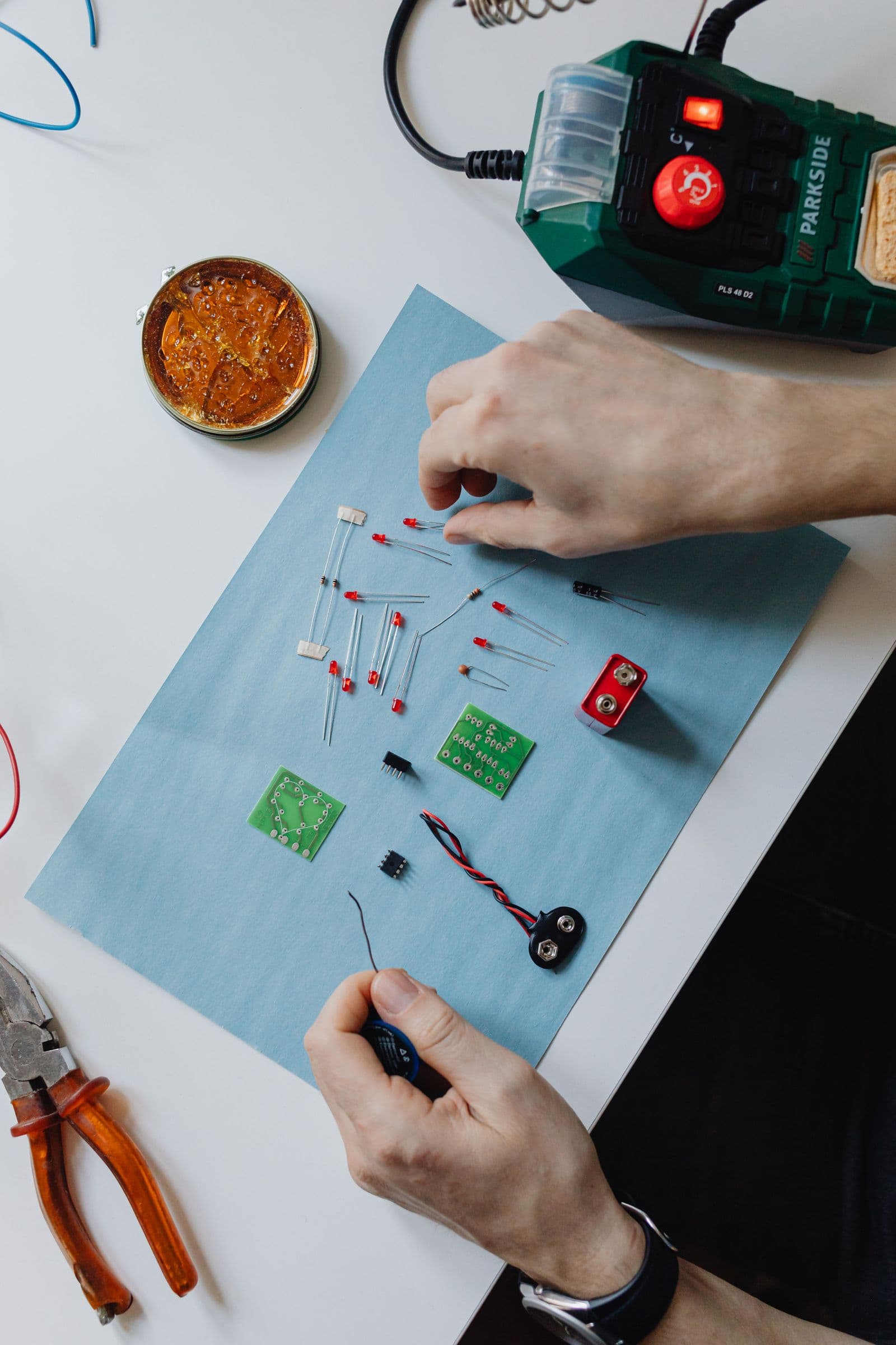 A soldering iron, pliers and cutters resting on a bench top mid-repair
