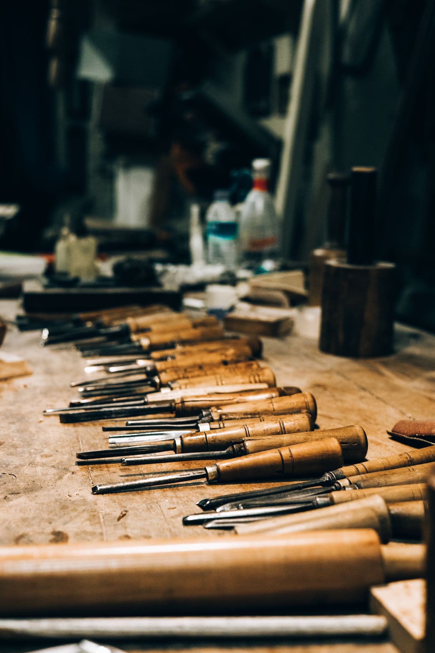 A row of well-used wood chisels laid out along a workbench