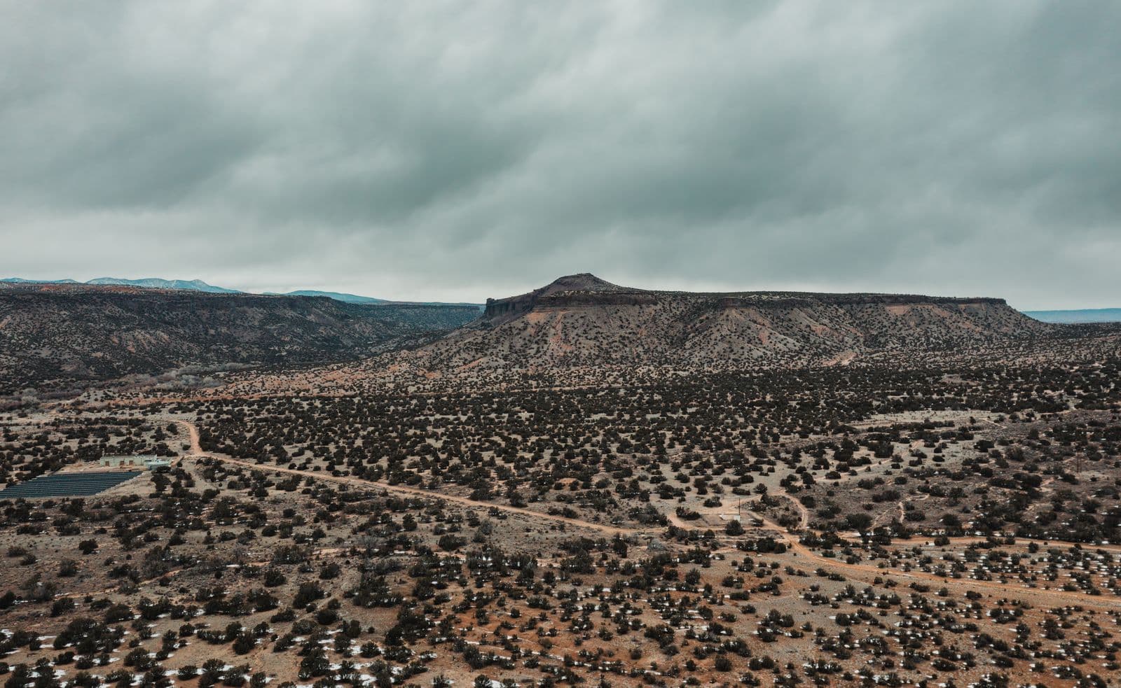 High-desert mesa with juniper scrub under a storm sky, northern New Mexico
