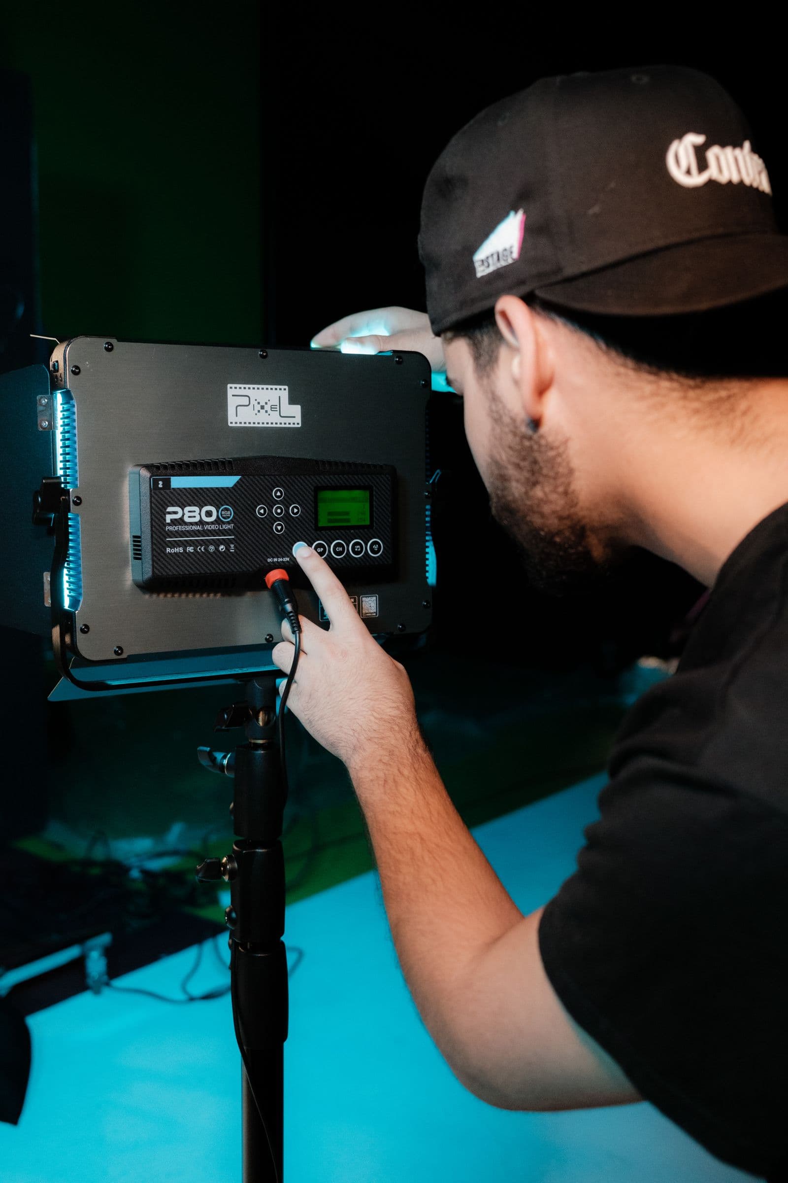 Technician dialing in an RGB light panel on a teal-lit studio set