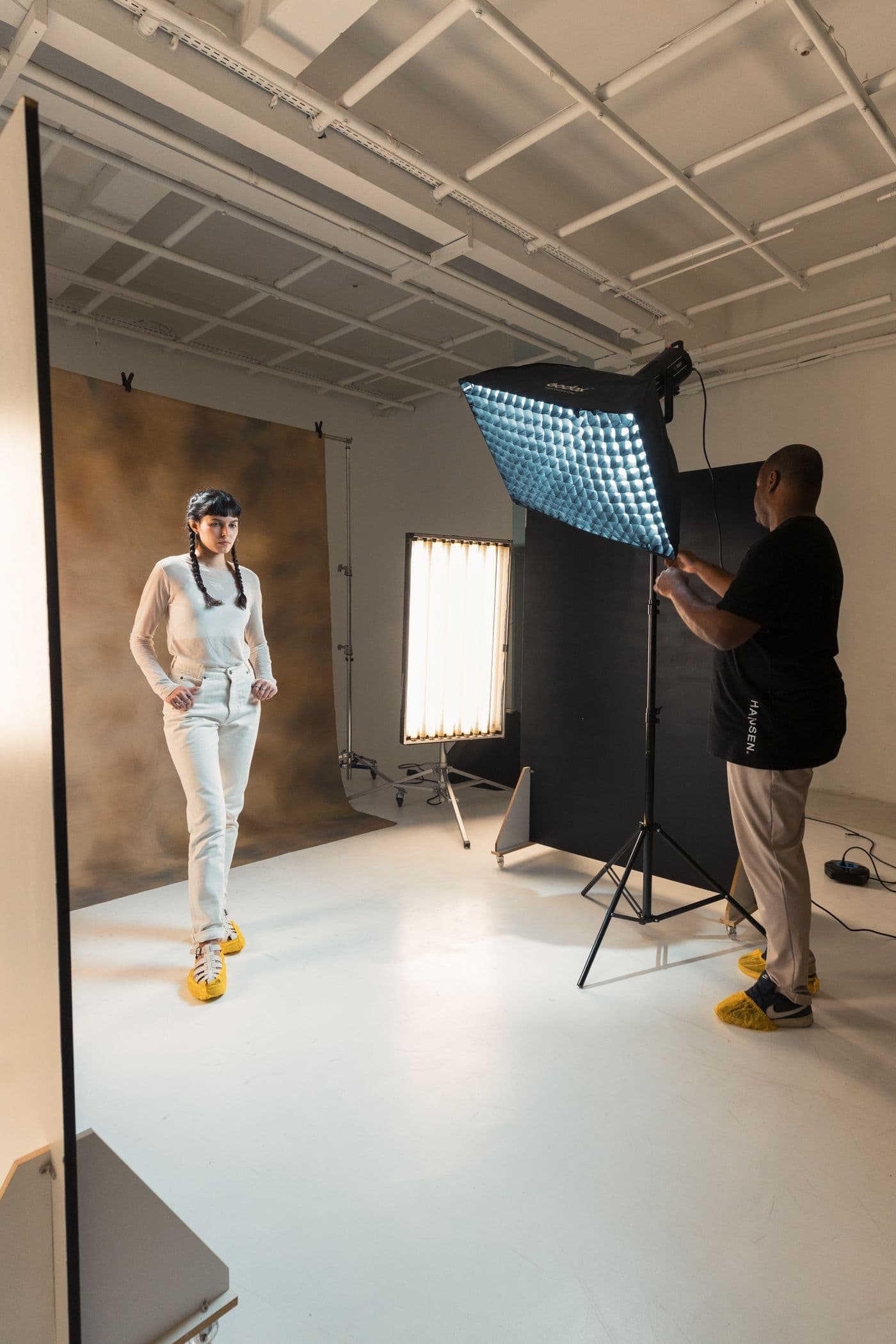 Photographer adjusting a gridded softbox mid-session with the subject in place