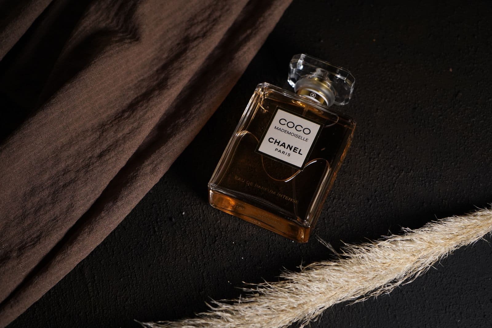 Perfume flacon on a dark textured surface in warm amber light