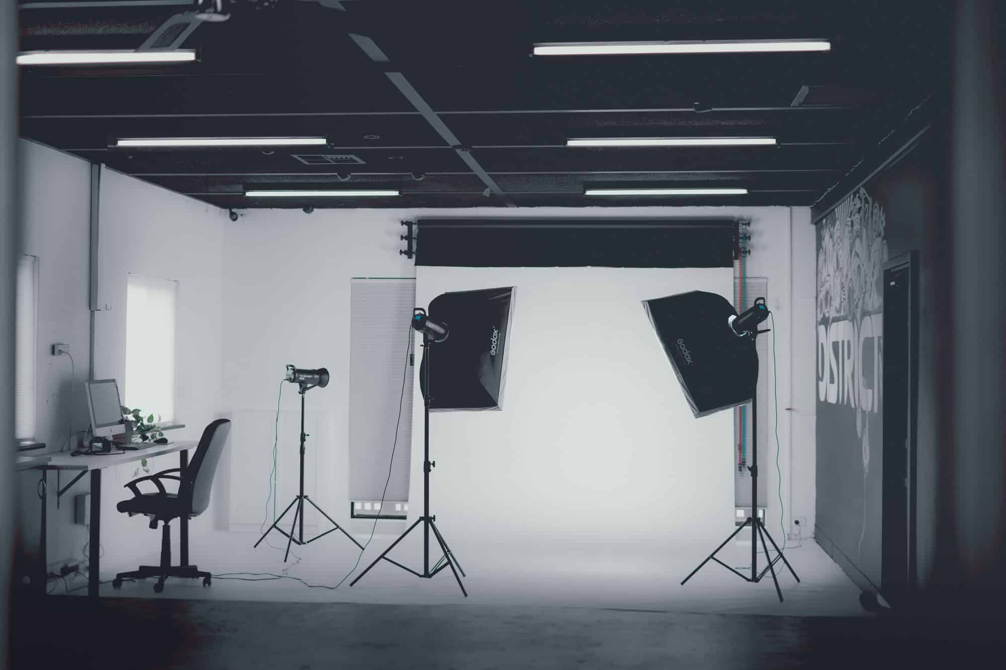 A blacked-out photography studio: softboxes and stands arranged against a white cyclorama.