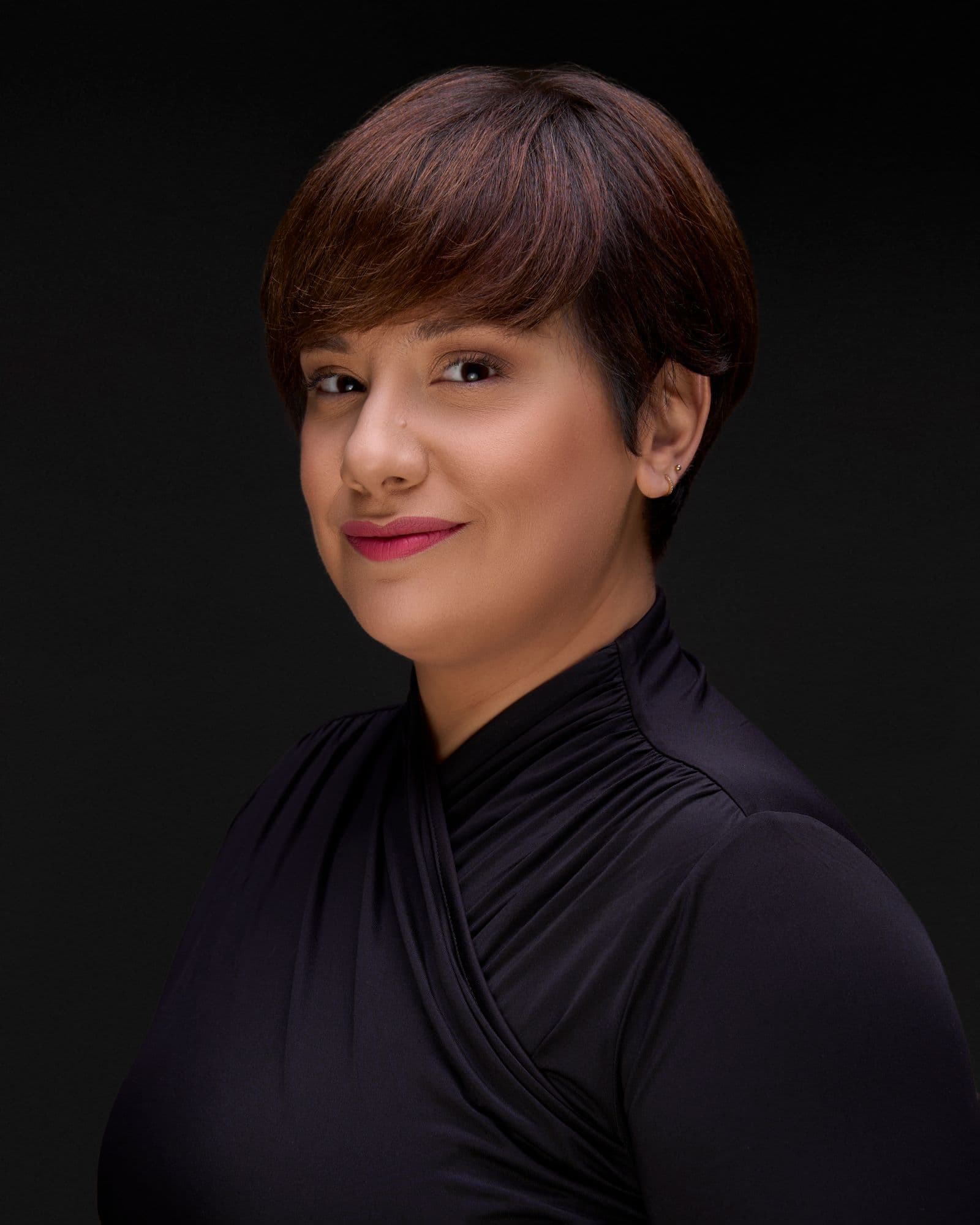 Polished studio headshot of a woman against a black background