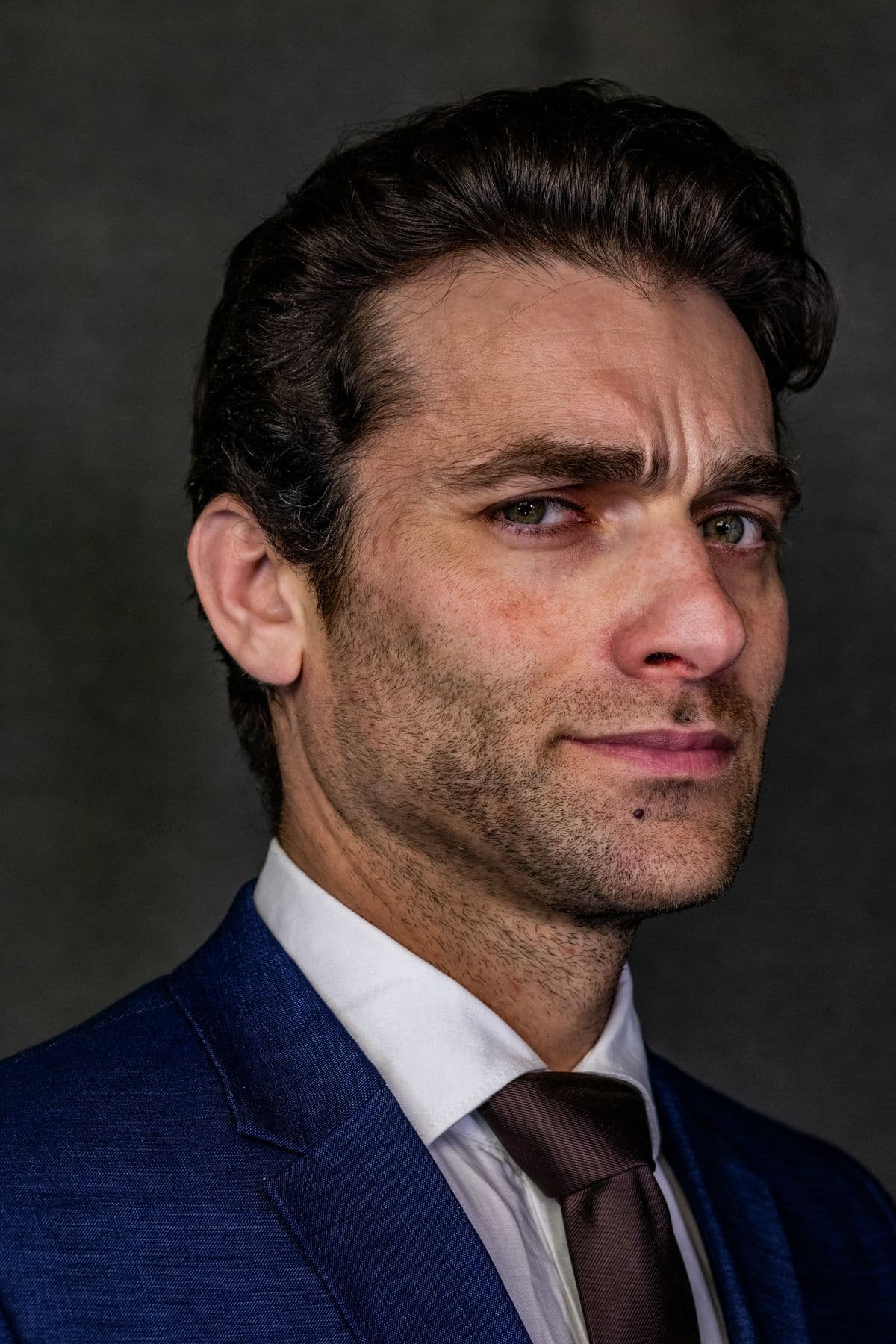 High-contrast close portrait of a man in a navy suit