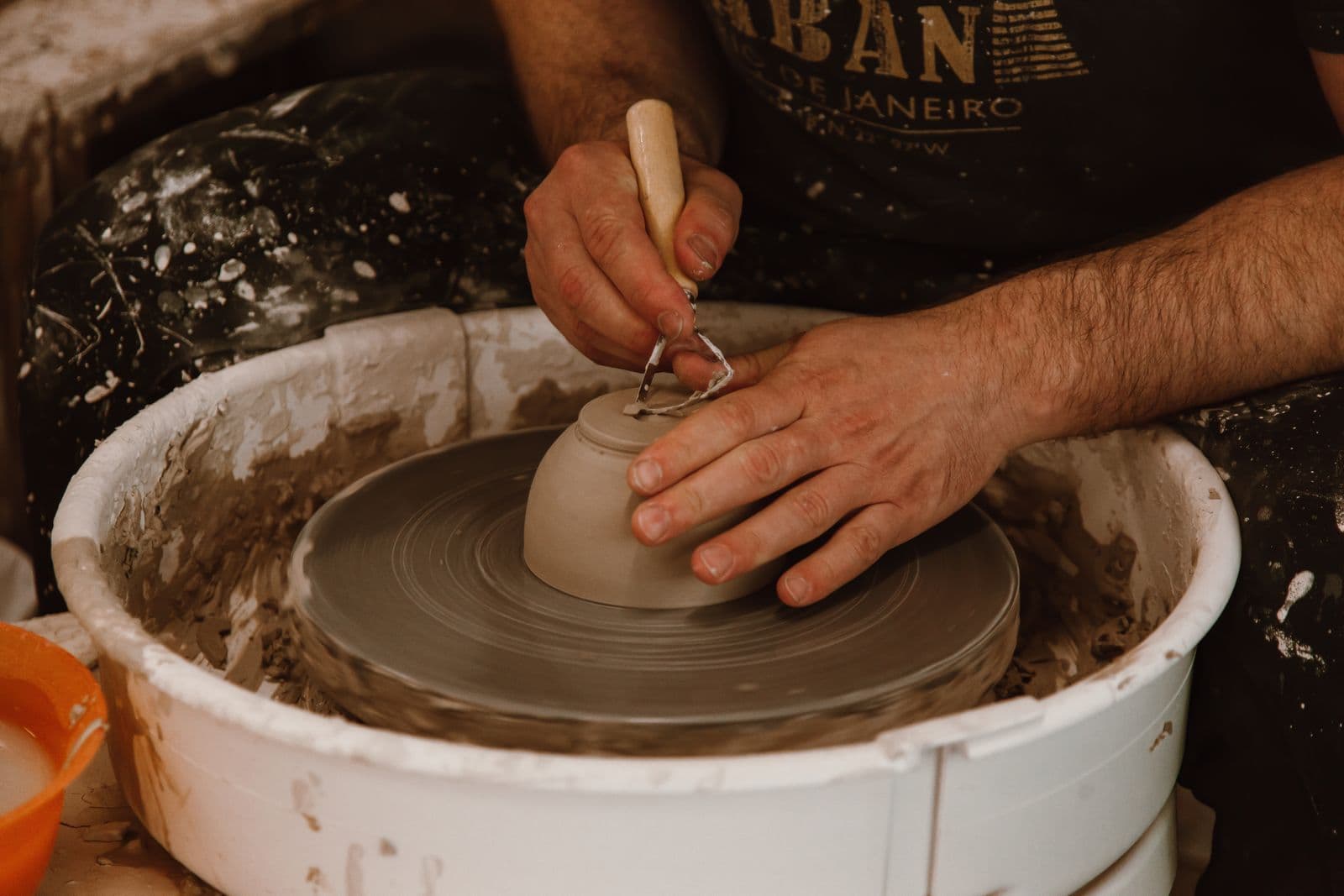 The potter's hands trimming an upturned bowl