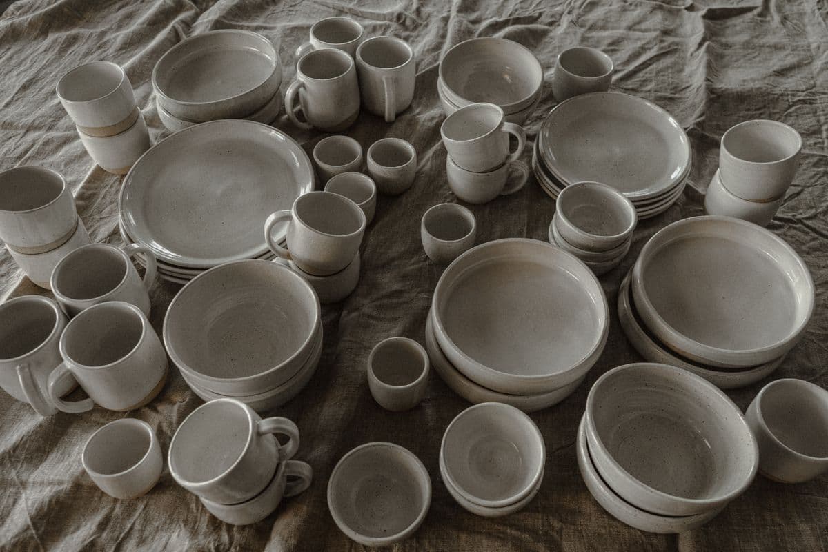A full speckled stoneware dinnerware setting laid out on linen