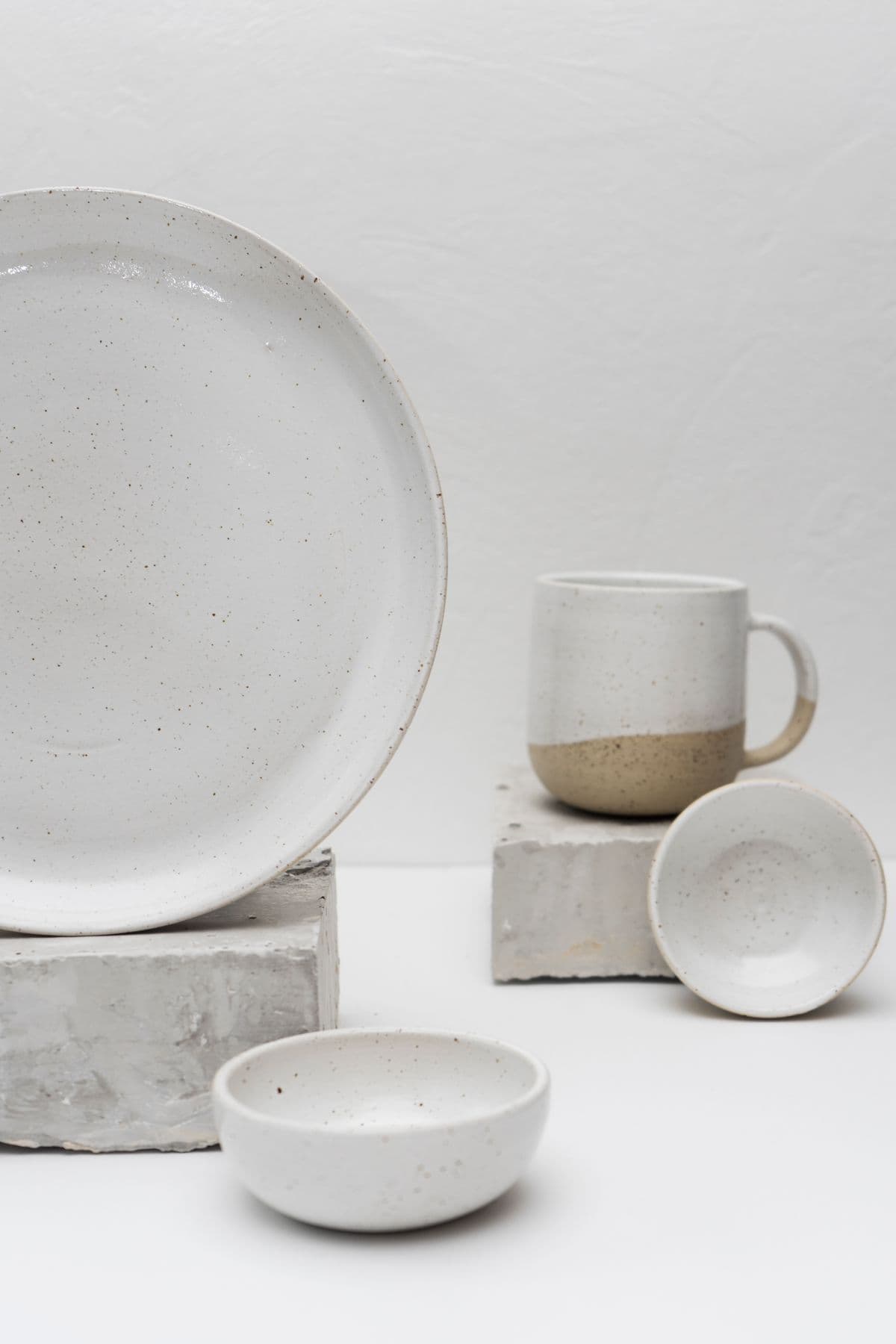 A speckled plate, mug, and bowls arranged as a still life
