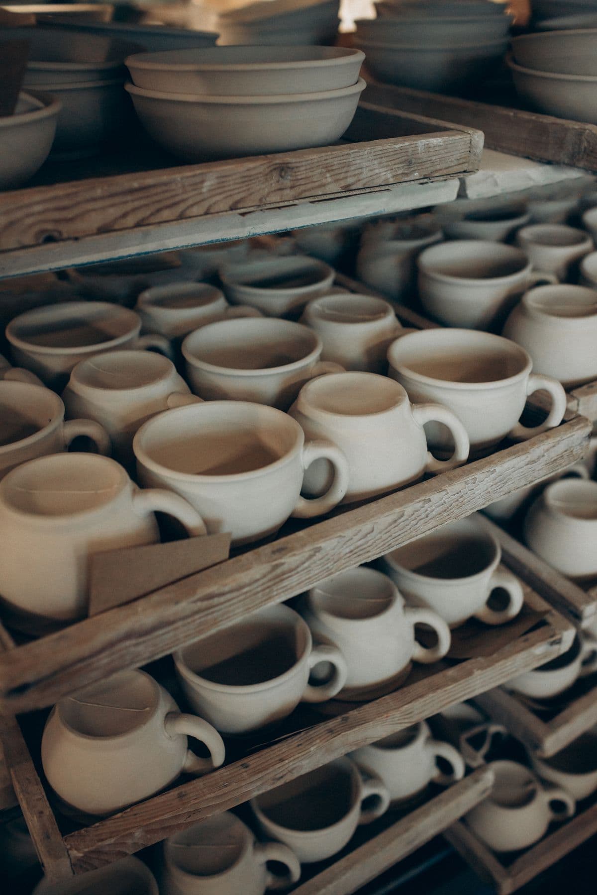 Drying racks of unglazed mugs and bowls in the studio