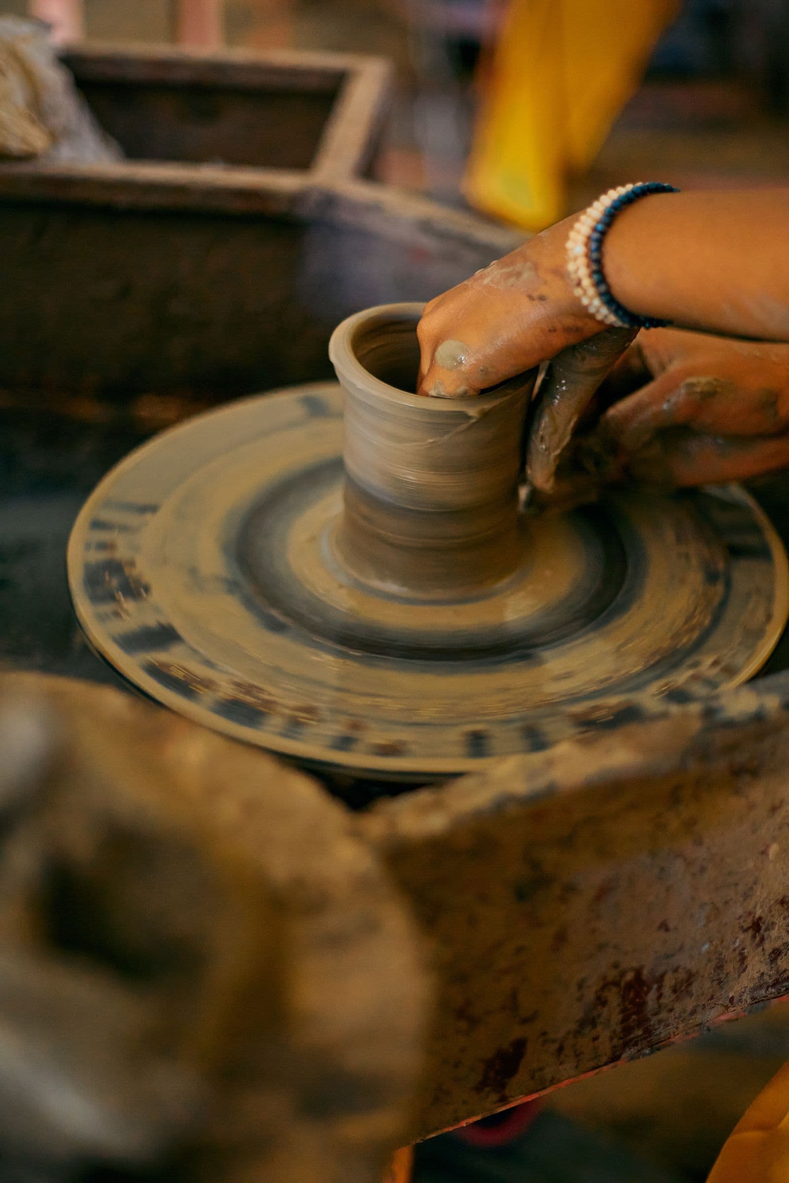 Hands centering a vessel on a spinning pottery wheel